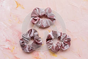 Three trendy velvet scrunchies on pink background