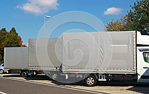 Three trucks with gray canvas standing in a row at a highway par