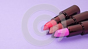 Three tubes of beautiful lipstick on a purple background