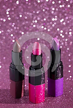 Three Tubes of Lipstick on a Bright Glittery Background