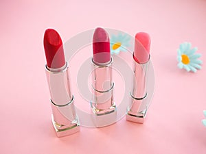 three tubes of lipstick on pink background, the concept of beauty