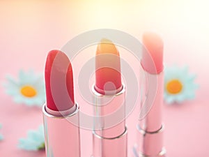 three tubes of lipstick on pink background, the concept of beauty