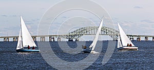 Three two person sailboats in front of the Great South Bay bridge on a windy December afternoon