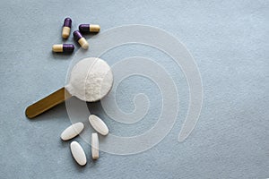 Three types of collagen in powder, tablets and capsules on a gray background. Measuring spoon with powdered hydrolyzed photo