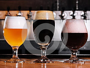 three types of craft beer in glasses on table in pub interior