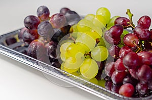Three types of green, red and black grapes on a silver tray