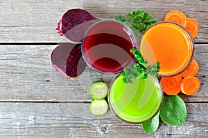 Three types of healthy vegetable juice above view on wood