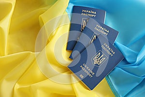 Three Ukrainian biometrical passports on folded waving flag of Ukraine country