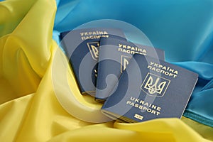 Three Ukrainian biometrical passports on folded waving flag of Ukraine country