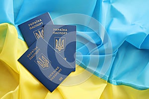 Three Ukrainian biometrical passports on folded waving flag of Ukraine country