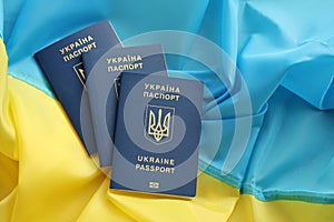 Three Ukrainian biometrical passports on folded waving flag of Ukraine country