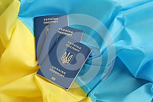 Three Ukrainian biometrical passports on folded waving flag of Ukraine country
