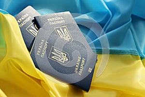 Three Ukrainian biometrical passports on folded waving flag of Ukraine country