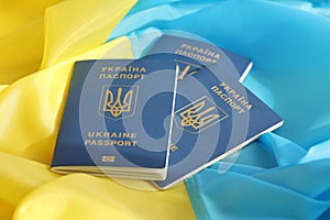 Three Ukrainian biometrical passports on folded waving flag of Ukraine country