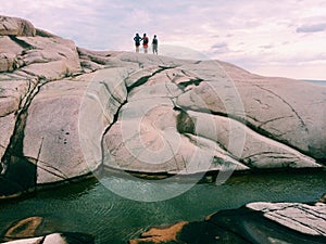 three undefined people on a rock in Sweden.