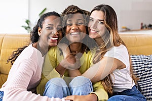 Three united beautiful smiling women sitting together on couch