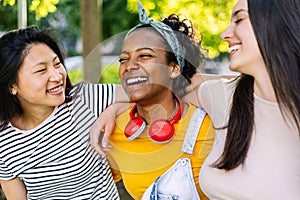 Three united multi-ethnic female friends having fun laughing together outdoor