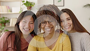 Three united multiracial female friends smiling at camera
