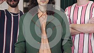 Three unrecognizable stylish confident retro men posing indoors in 1980s. Young Caucasian dandy adjusting velvet jacket