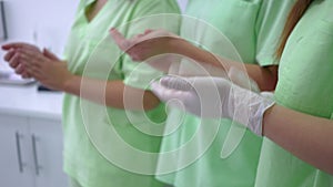 Three unrecognizable women in laboratory uniform clapping standing in medical clinic indoors. Caucasian employees