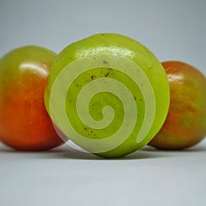 three unripe but fresh looking tomatoes on a white background