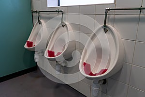three urinals in a mens public bathroom or mens public toilet