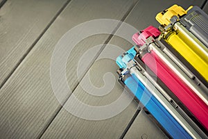 Three used toner cartridges in a color laser printer on gray wooden background for recycling photo