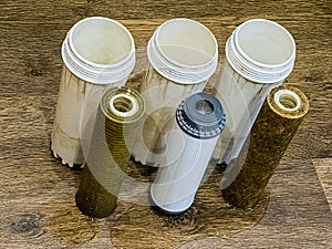 Three used water filters with traces of dirt, clay and contaminants. Replacing multi-stage water filter cartridges