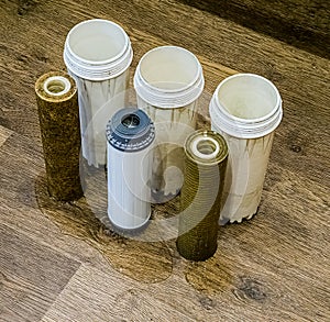 Three used water filters with traces of dirt, clay and contaminants. Replacing multi-stage water filter cartridges