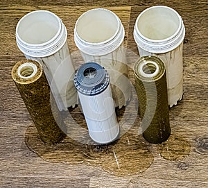 Three used water filters with traces of dirt, clay and contaminants. Replacing multi-stage water filter cartridges