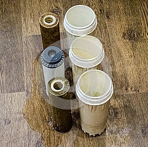 Three used water filters with traces of dirt, clay and contaminants. Replacing multi-stage water filter cartridges