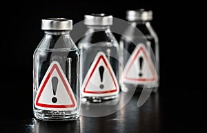 Three vaccine bottles with red triangle exclamation mark sign on label, black background