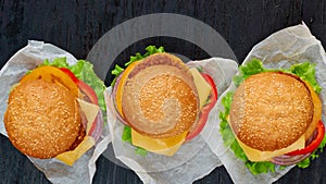 Three vegetarian burgers with falafel, salad, onion, cheese, tomatoes on black background. Traditional Middle Eastern fast food