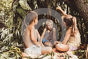 Three village children are playing in a hut which they themselves have built from leaves and twigs. Wooden house in the forest