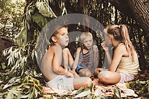 Three village children are playing in a hut which they themselves have built from leaves and twigs. Wooden house in the forest