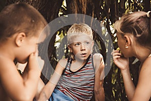 Three village children are playing in a hut which they themselves have built from leaves and twigs. Wooden house in the forest