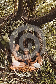 Three village children are playing in a hut which they themselves have built from leaves and twigs. Wooden house in the forest