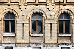 Three vintage arched windows in a wall of yellow bricks. Green - the colors of sea wave glass in a maroon dark red