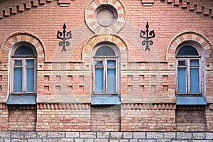 Three vintage arched windows in a wall of yellow bricks. Green - the colors of sea wave glass in a maroon dark red