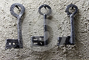 Three vintage black keys on white wall