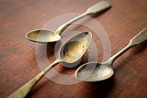 Three vintage metal spoons on a dark background