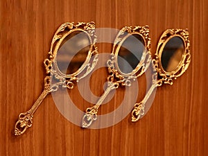 three vintage round golden hand mirrors crafted in bronze