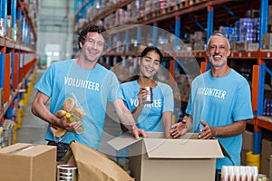 Three volunteers packing eatables in cardboard box photo