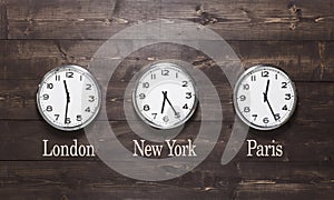 Three wall clocks on different time zones