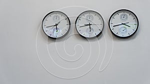 Three wall clocks showing time in different capitals of the world