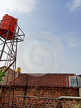 Three water tanks on rooftops under a clear blue sky.