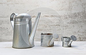 three watering can arranged from largest to smallest on white wooden background