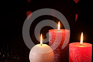 Three wax flame candlelight in dark romantic light on hearts background, love dating, Valentine`s day