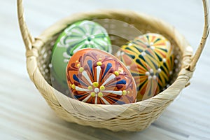 Three wax painted Easter eggs in light brown wicker basket