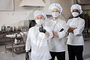 Three well-dressed chefs standing together in the professional kitchen